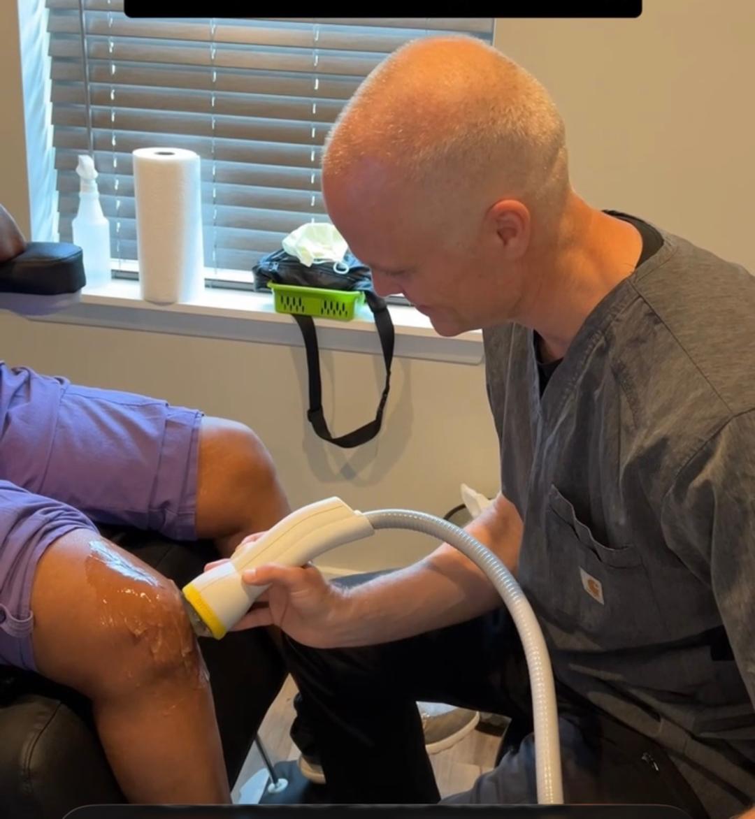Dr. Dan Klein realizando Terapia SoftWave en la rodilla de un paciente en Upper Darby PA